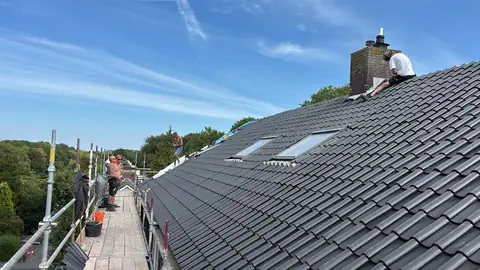Dakdekkers aan het werk op het dak en op de steiger tijdens de renovatie