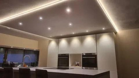 Inbouwspots in het verlaagde plafond, gericht op de kastenwand van de keuken